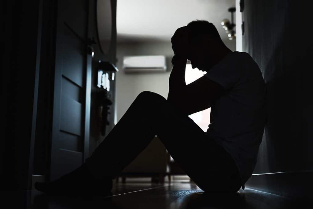 Man ervaart een moeilijk moment alleen thuis, worstelend met de impact van drugsverslaving op zijn leven.