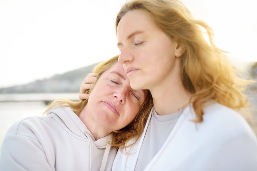 Moeder zoekt steun en troost bij haar dochter tijdens een emotioneel moment.